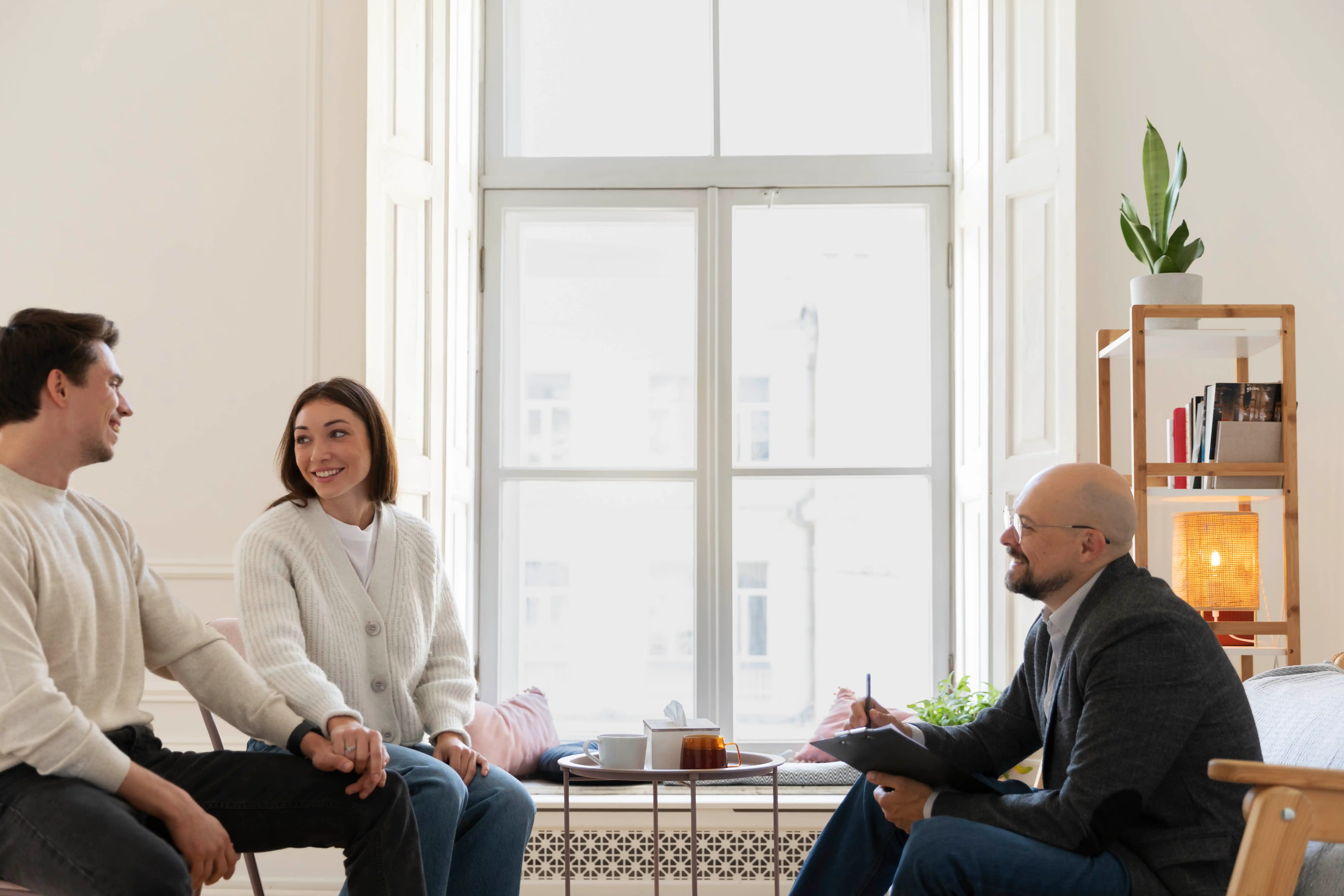 A man and woman converse with another couple in a cozy living room setting.