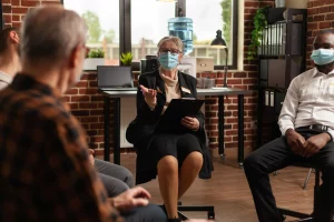 A group of masked individuals collaborating in an office setting, emphasizing safety and health protocols.